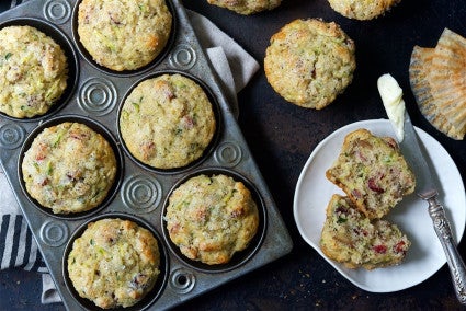 Zucchini lemon muffins in a baking tin and halved on a plate