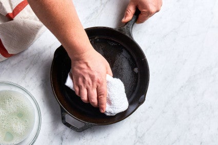 cast iron pan getting dried with a towel