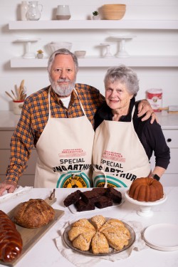 Frank and Brinna Sands standing side-by-side in front of an assortment of baked goods