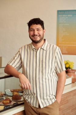 Arturo standing in front of his bakery's pastry case