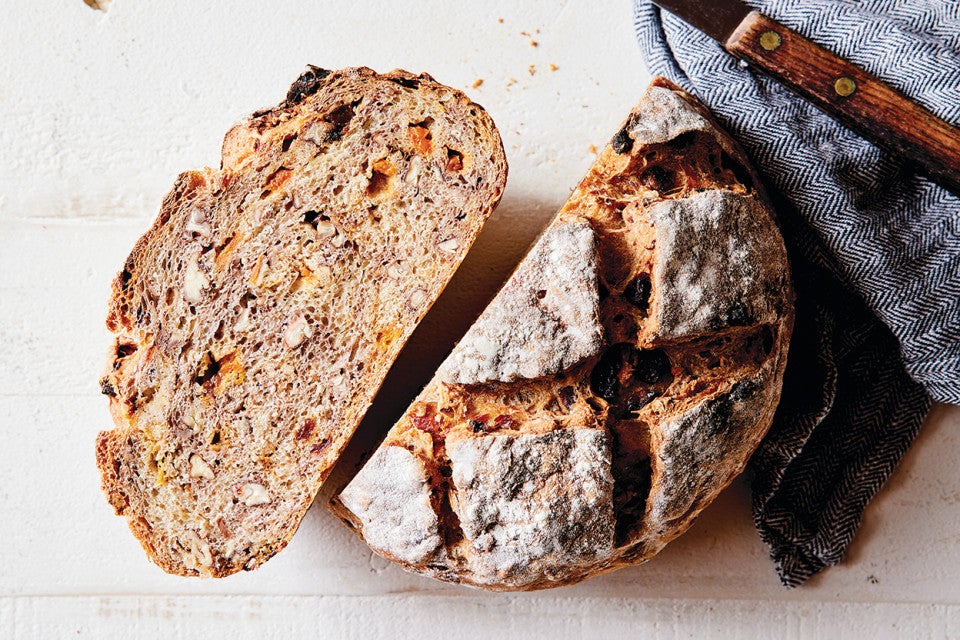 Loaf of No-Knead Harvest Bread, this fruit bread has been cut in half showing that itis filled with dried fruits and nuts.