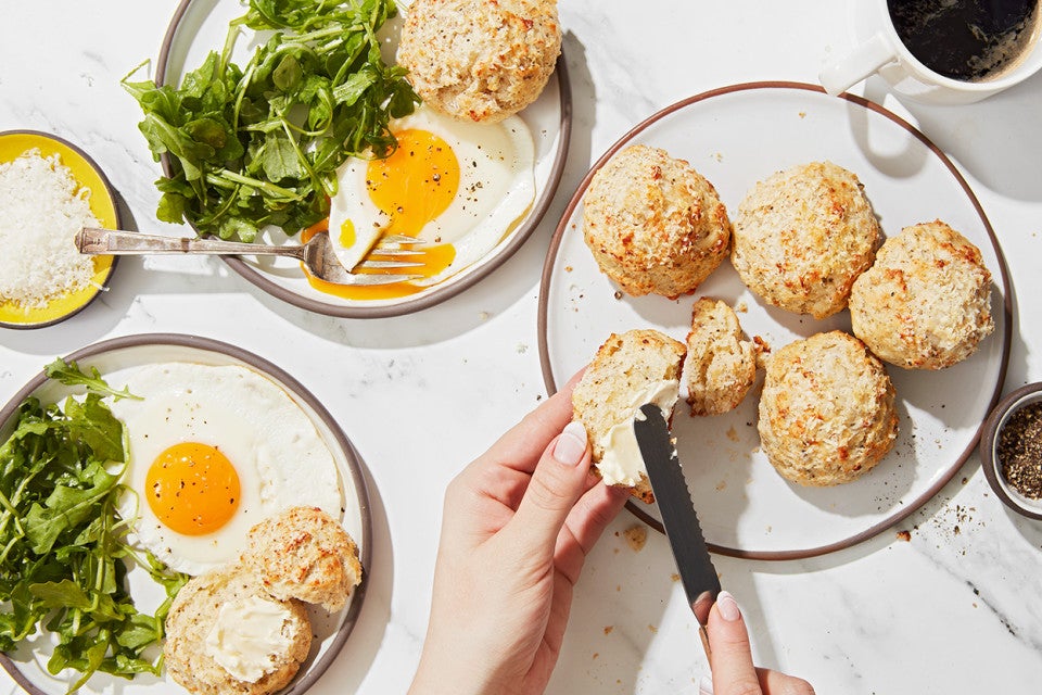 A baker buttering a Cacio e Pepe (Cheese and Pepper) Scone