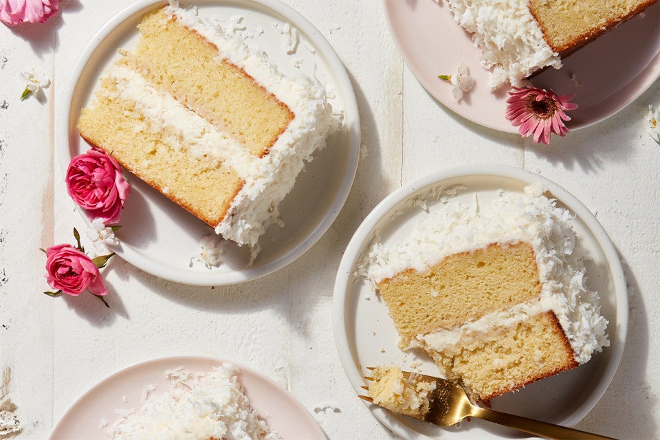 A few slices of two-layer Old-Fashioned Coconut Cake on plates, decorated with edible flowers