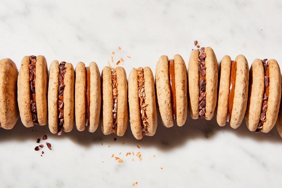 Cola de Mono Alfajores (dulce de leche sandwich cookies) lined up, coated in different garnishes