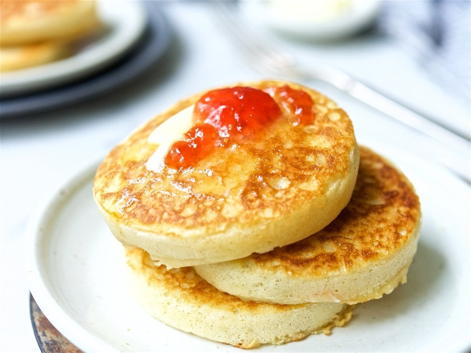 A stack of sourdough crumpets topped with butter and jam