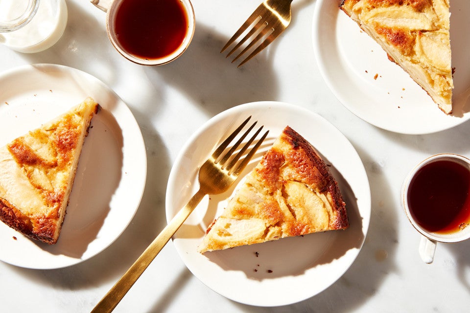 Mostly Apples Apple Cake cut into slices and plated with forks and tea, ready to be eaten