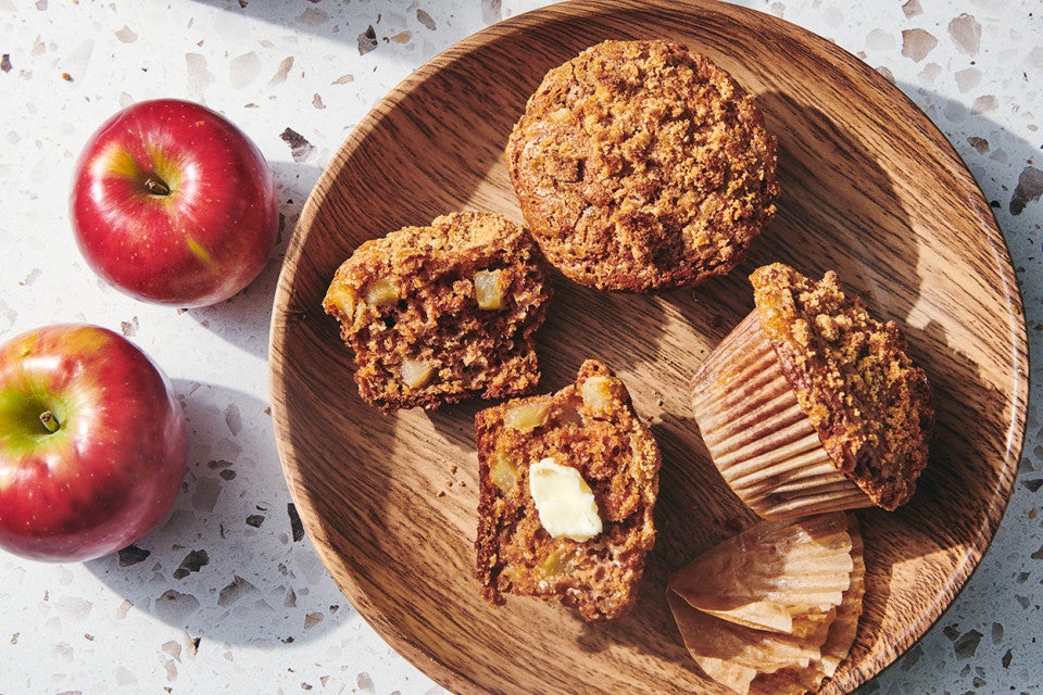 Brown sugar-topped apple muffins on a plate with a pat of butter.