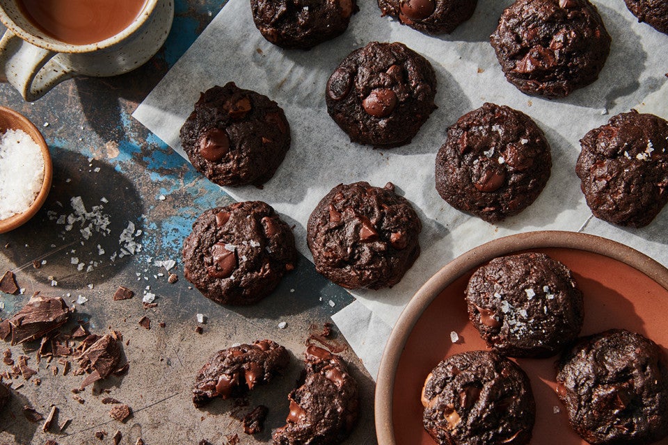 Dark chocolate brownie espresso cookies topped with flaky sea salt on a kitchen counter