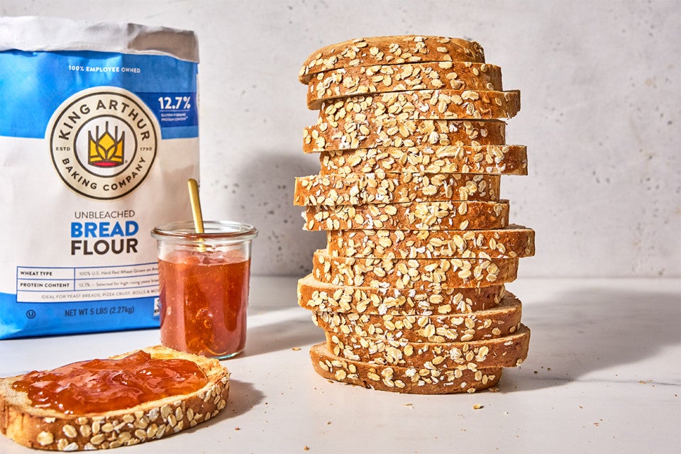 Back-of-the-Bag Oatmeal Bread towered high next to a slice with jam