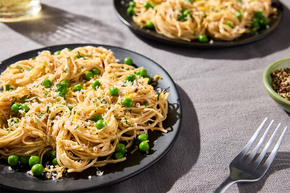 Whole Wheat Pasta with shredded cheese and peas on a dinner plate