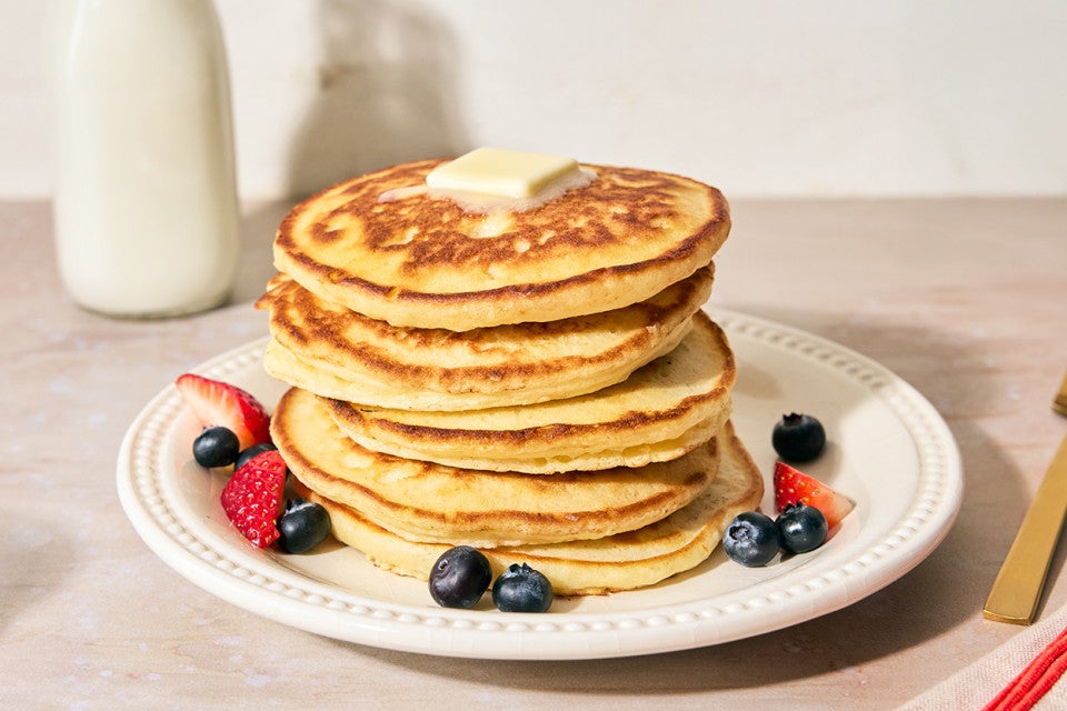Easy Buttermilk Pancakes stacked high on a plate with fresh fruit