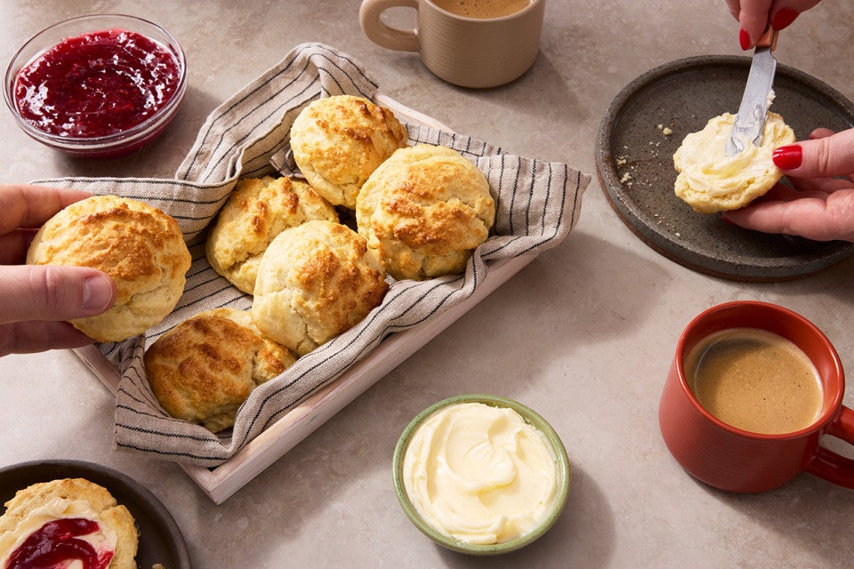 Easy Drop Biscuits with Buttermilk Biscuit Flour on a dish towel while another has butter spread on it