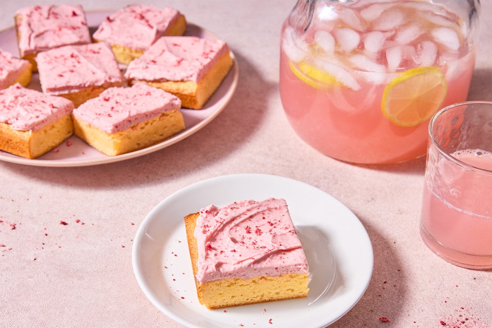 Strawberry Lemonade Bars served on a plate with a pitcher of strawberry lemonade