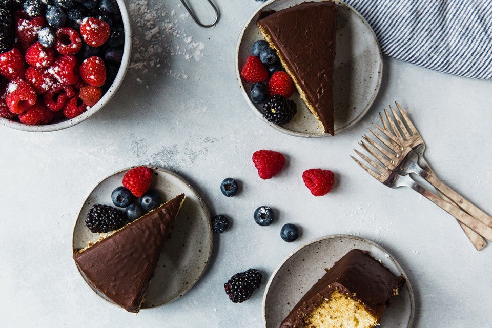 Classic Yellow Cake with Fudge Frosting served on plates with berries
