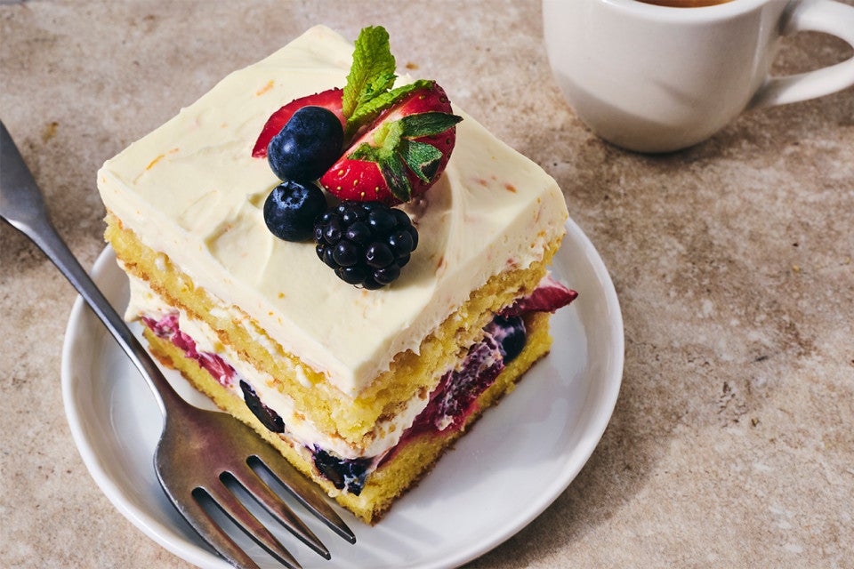A slice of Berry Tiramisu on a plate with a cup of coffee