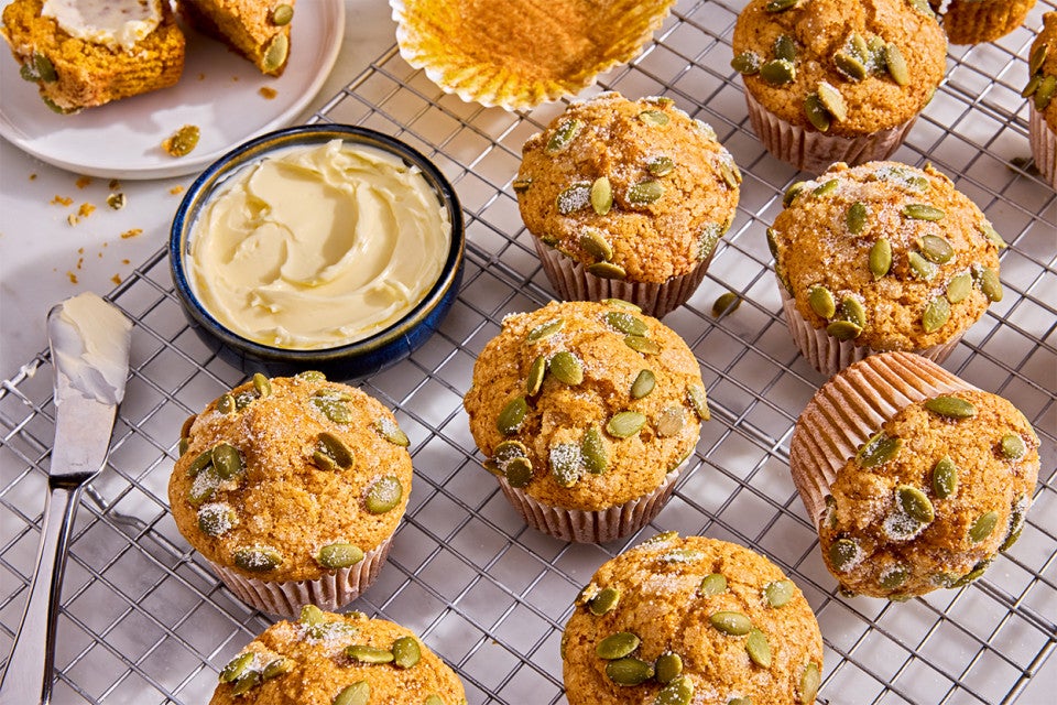 Easy Pumpkin Muffins on a cooling rack with a dish of butter