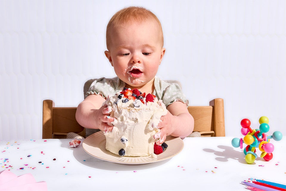 A baby attacking her First Birthday Smash Cake 