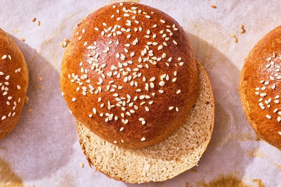 100% Whole Wheat Hamburger Buns sliced and on parchment paper