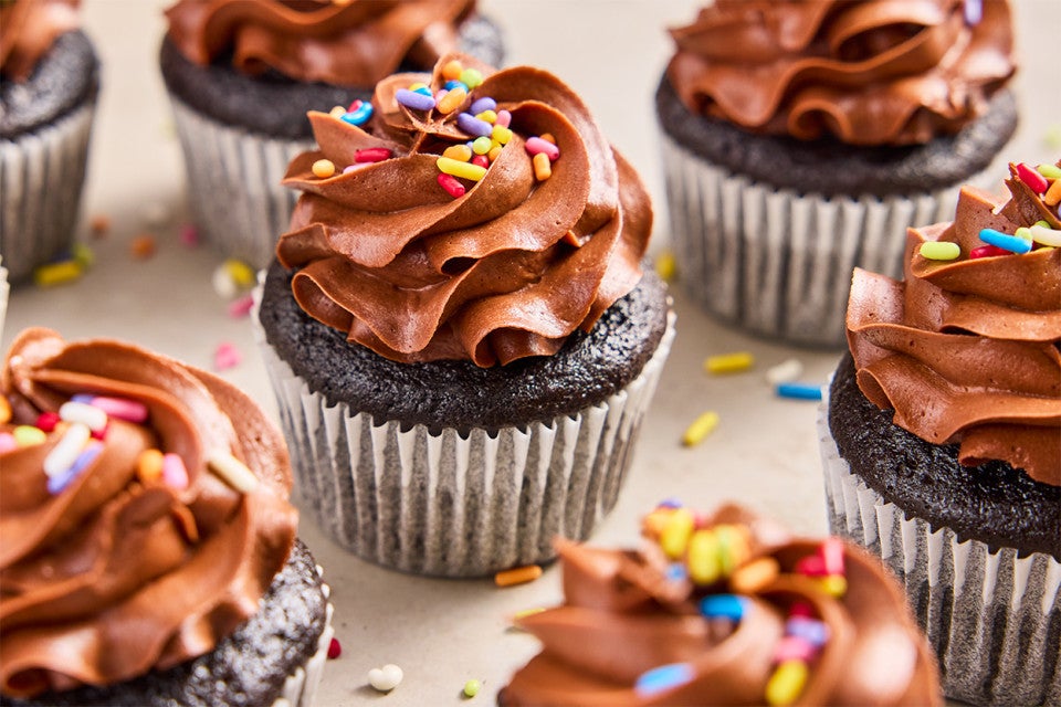 A bunch of Bake Sale Fudge Cupcakes topped with rainbow sprinkles