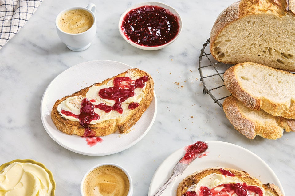 Extra-Tangy Sourdough Bread served on a plate with butter and jam