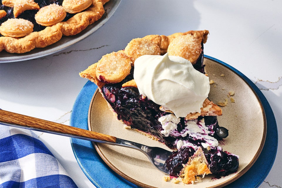 A slice of Fresh Blueberry Pie served on a plate with whipped cream
