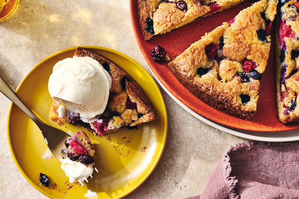 A slice of Late Summer Berry Torte on a plate with a scoop of vanilla ice cream