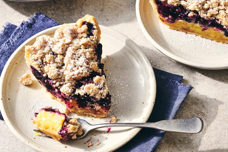 A slice of Lemon-Blueberry Streusel Pie on a plate with a piece taken out on a fork