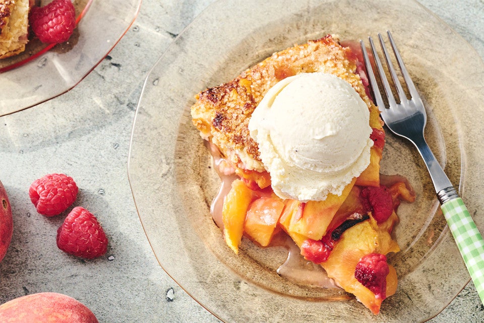 A slice of Peach Galette on a plate with a scoop of vanilla ice cream