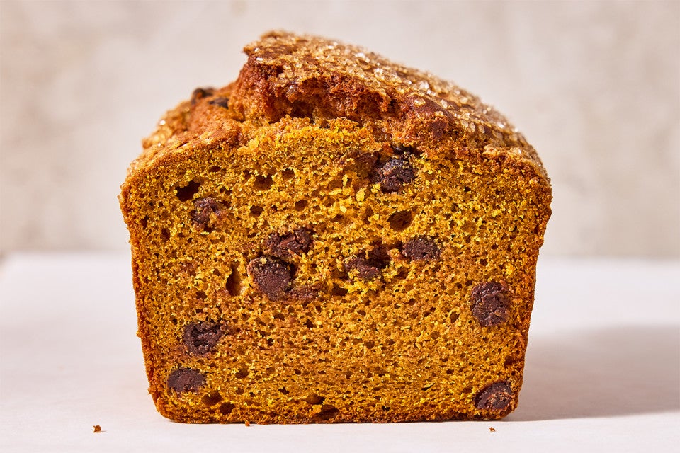 A loaf of The Most Pumpkin Pumpkin Chocolate Chip Bread cut into showing the interior
