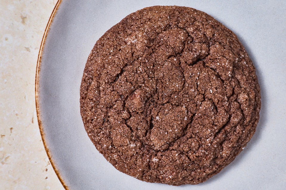 Overhead photograph of a single soft chocolate sugar cookie on a light colored plate.