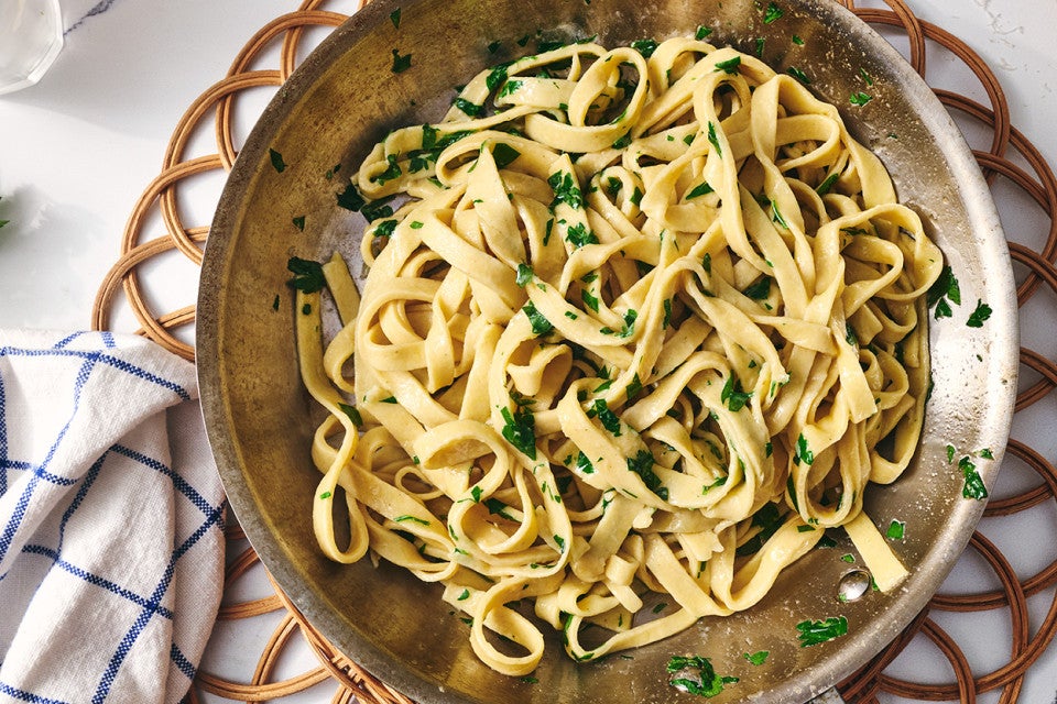 A bowl of gluten free pasta dressed with parmesan and parsley.