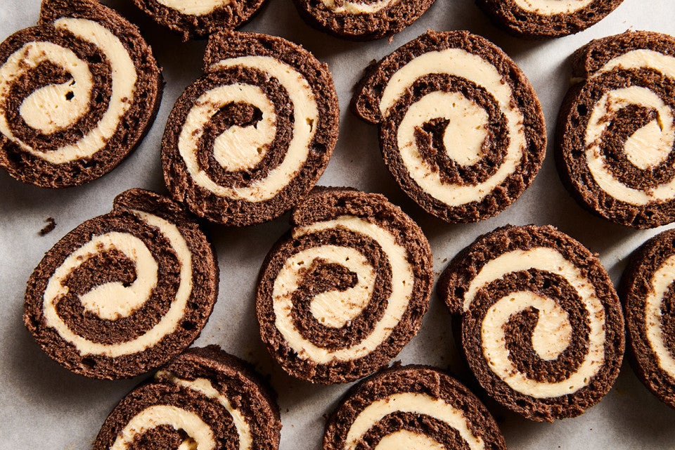 Sliced pinwheels of chocolate cake filled with Cookie Butter Whipped Ganache all laying side by side on a sheet tray.