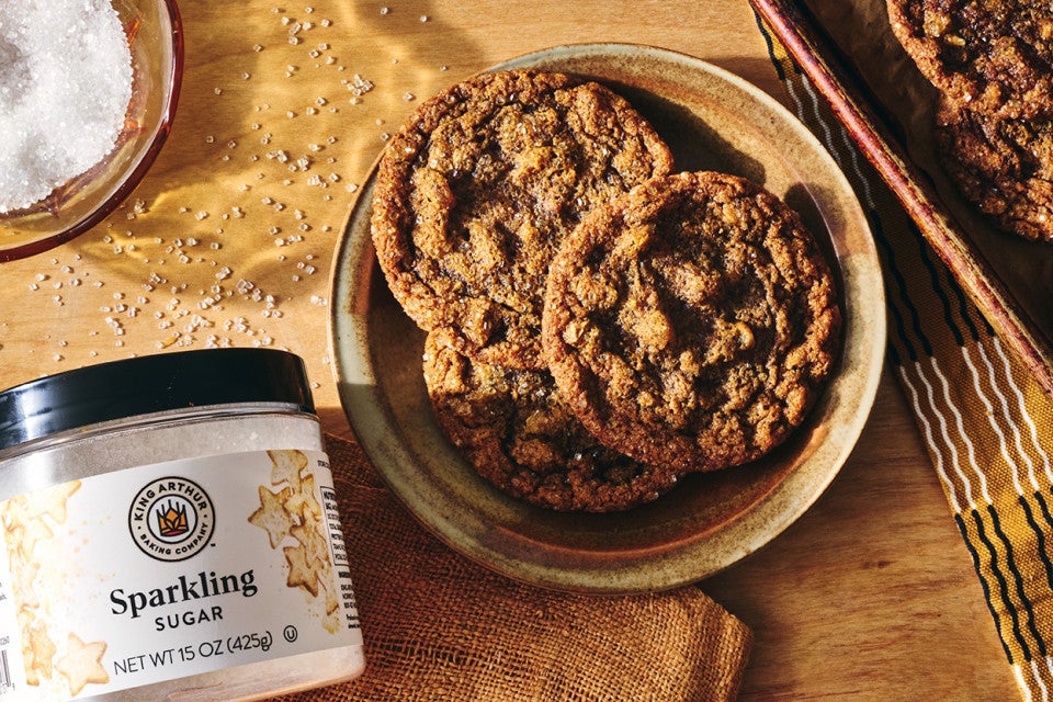 Cape Cod Soft Molasses Cookies shown on a plate with King Arthur Baking's Sparkling Sugar in the bottom left corner of the frame.