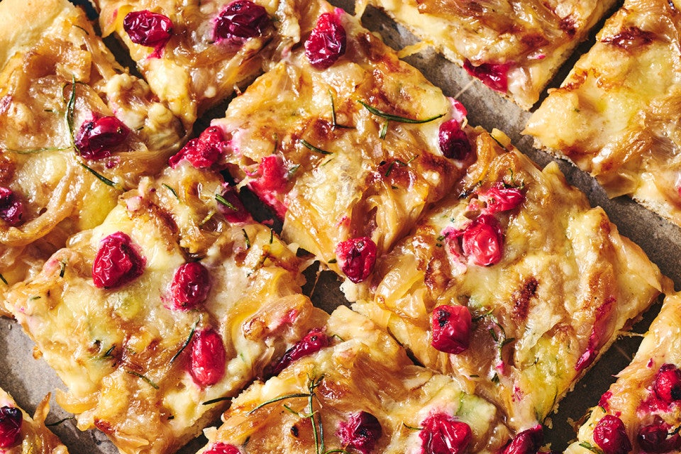Sliced Caramelized Onion and Brie Pizza showing a golden baked top dotted with pomegranate, brie, and caramelized onion.