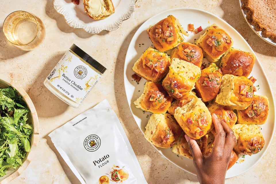 Loaded Baked Potato Dinner Rolls on a plate with someone grabbing one