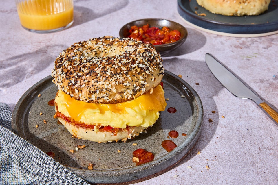 A breakfast sandwich with egg and cheese between a delicious everything bagel on a plate.