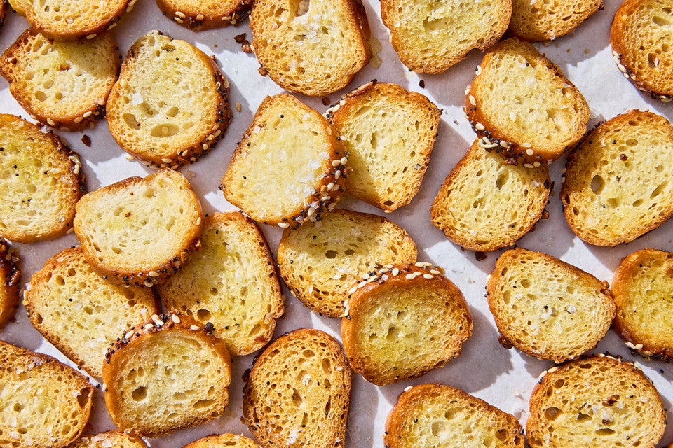 Multiple everything bagel chips laid out on a sheet tray.