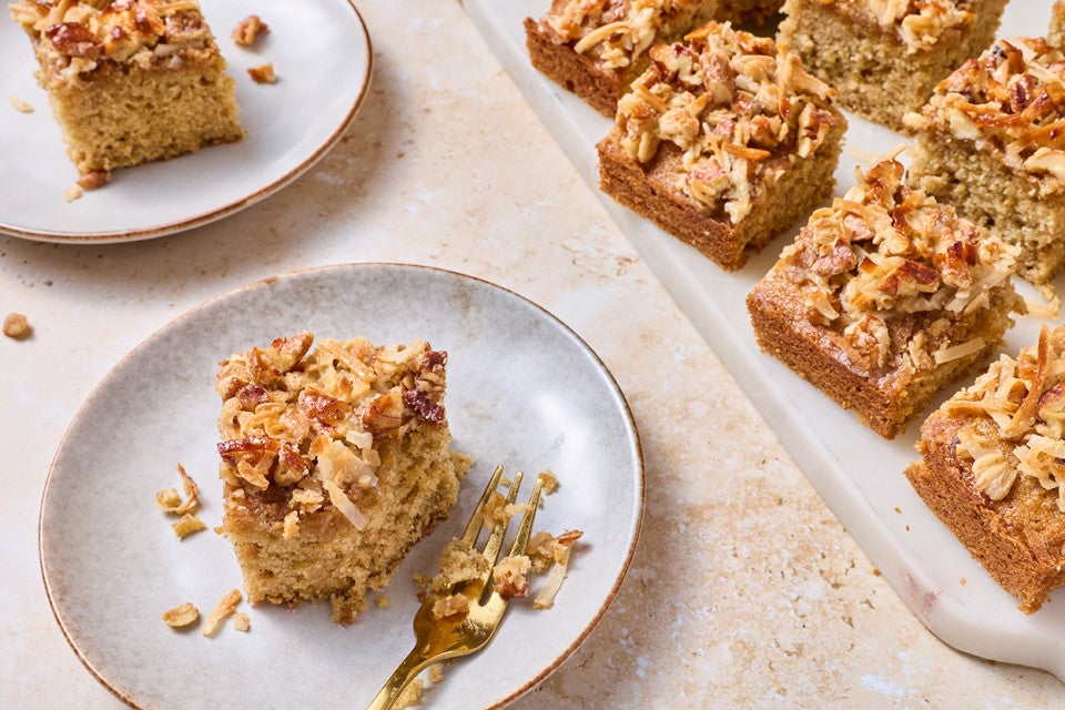 A slice of Oatmeal Cake on a white plate with other cake slices on the edge of the photograph.