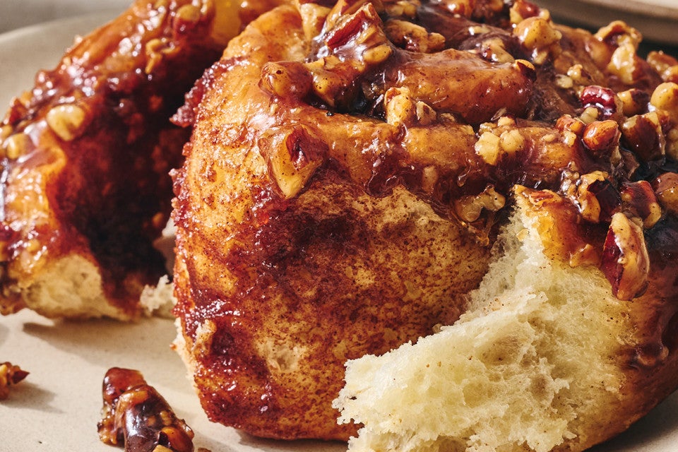 Detailed photograph of a dark brown sticky bun peeled apart showing a sweet and perfectly baked interior.