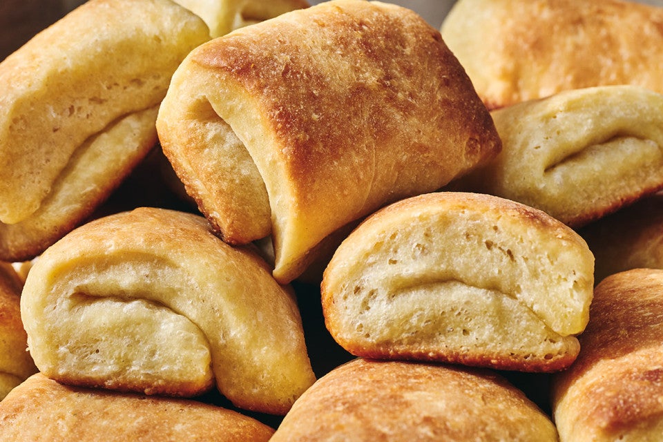 Detail shot of Parker House Rolls stacked together showing their classic fold and lovely brown exterior.