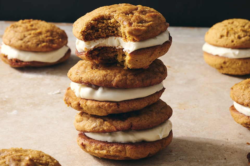 Pumpkin Whoopie Pies photographed in a stack on a counter showing the layers of pumpkin cookie and creamy filling.