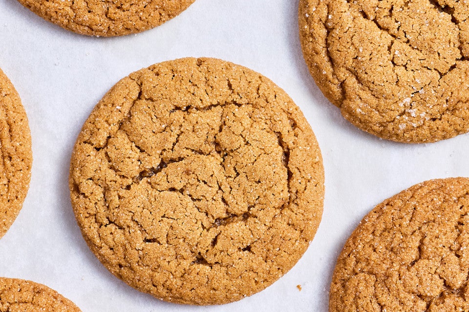 Soft Brown Sugar Cookies laid out on white parchment showing the top of the cookies with a soft cracked top and dark golden hues.