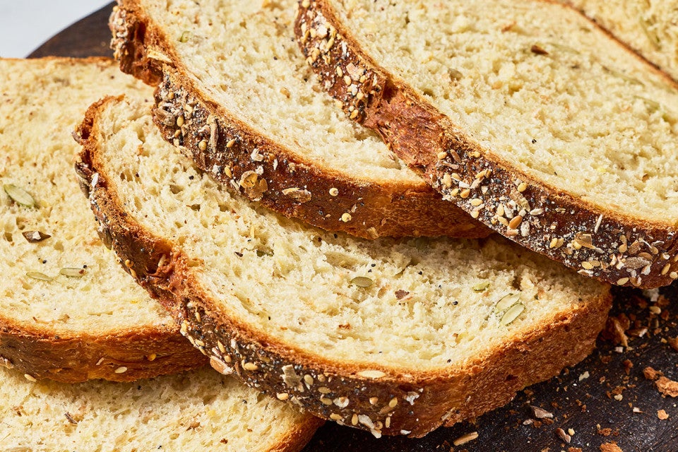 Slices of Multigrain Protein Bread arranged on top of each other showing the crust and golden interior.
