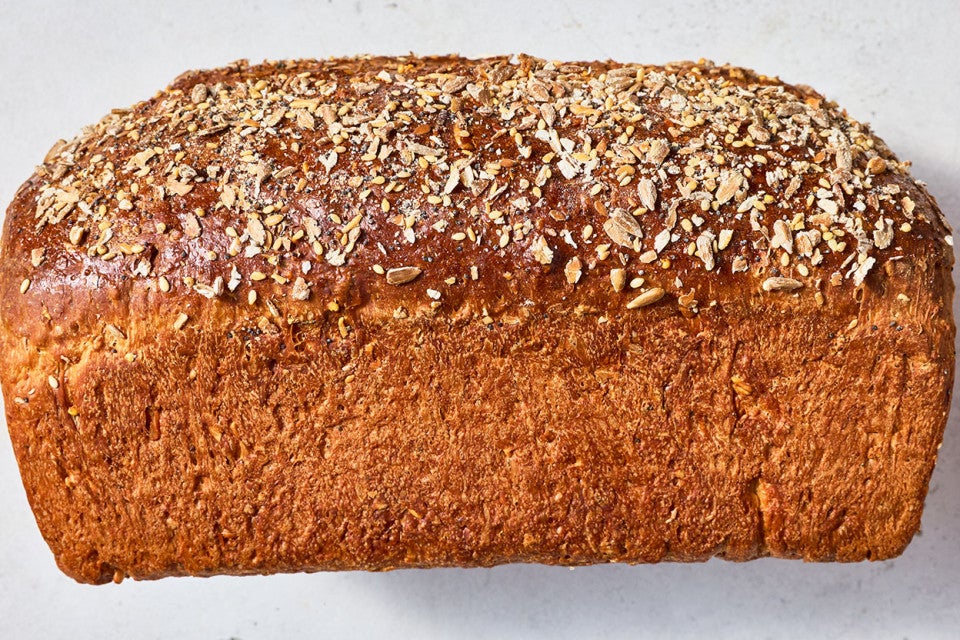 Multigrain Protein Bread see from the side to show the dark brown crust and seed covered top.