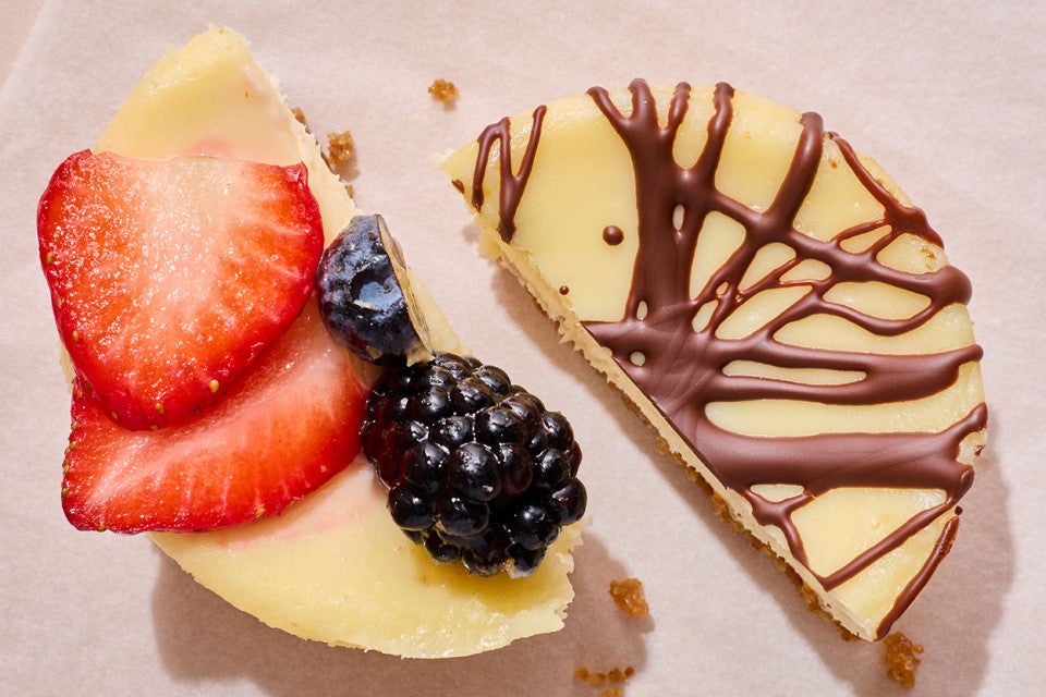 Two Mini Cheesecakes - one with fresh strawberry and blackberry, the other with chocolate - cut in half and placed next to each other.