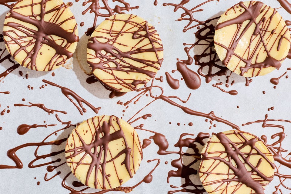 Mini Cheesecakes drizzled with chocolate photographed looked down to show an almost abstract scene.