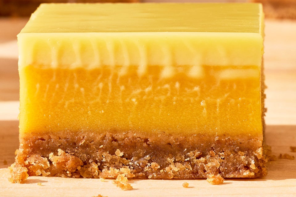 A Passionfruit Bar from the side and stacked to show smooth and creamy layers of passionfruit and crust.