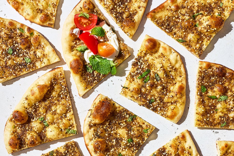 Slices of Za’atar Manakeesh seen from above and arranged randomly on a countertop.