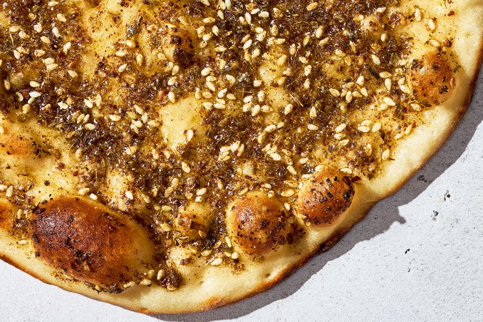 A single Za’atar Manakeesh showing the perfectly browned bubbles of the flatbread and tasty topping.