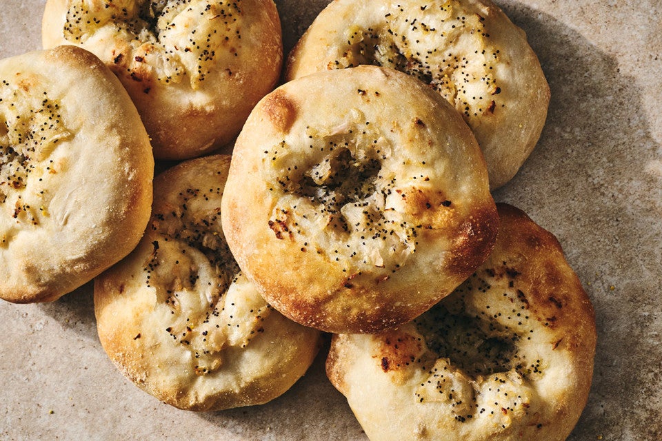 Classic Bialys stacked together with herbs and golden crust on each.